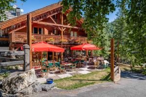 a wooden house with tables and chairs and umbrellas at Hôtel Ecureuil in Vars
