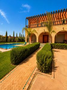 a building with a swimming pool and palm trees at VILLA Les 3 Palmiers in Amezrou
