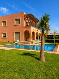 a house with a palm tree and a swimming pool at VILLA Les 3 Palmiers in Amezrou