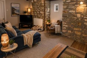 a living room with a blue couch and a stone wall at Picton-House in St Clears