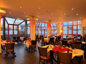 a dining room with tables and chairs and windows at Hotel Mozart in Traunreut