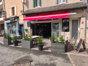 a restaurant with potted plants in front of a building at Le MUSTANG in Saint-Geniez-dʼOlt +2 photos