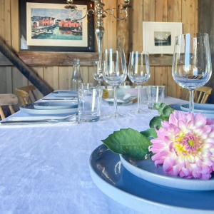 a table with wine glasses and a pink flower on it at Seaside Boathouse In Veiholmen in Smøla +22 photos