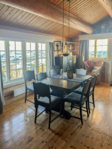 a dining room table and chairs in a room with windows at Cozy, Magical Mountain Cabin With Trails in Etnedal