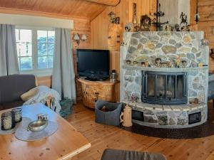 a living room with a stone fireplace and a television at Cozy, Magical Mountain Cabin With Trails in Etnedal