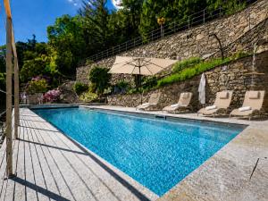 a swimming pool with chairs and an umbrella at Villa Amore in Cannobio