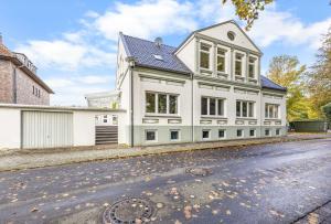 a white house with a lot of windows on a street at Ferienwohnung Edo Wiemken in Jever +4 photos