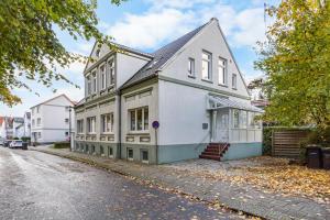 a white house on a street with trees at Ferienwohnung Edo Wiemken in Jever