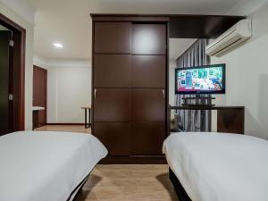 a hotel room with two beds and a tv at Mercure Jaragua do Sul in Jaraguá do Sul
