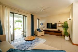 a living room with a couch and a tv at Chic poolside haven 3BR steps from the beach in Cap Malheureux