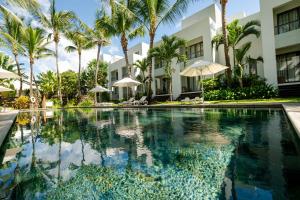 a swimming pool in front of a building with palm trees at Chic poolside haven 3BR steps from the beach in Cap Malheureux