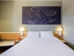 a bedroom with a large white bed with two lamps at Ibis Granada in Granada
