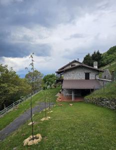 a house on a hill with a tree in the yard at Eco Mountain Green House in Bienno