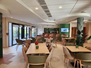 a restaurant with tables and chairs and a kitchen at DOMITYS - Les Arilles in Ifs