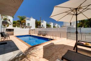 a patio with an umbrella and a swimming pool at Nissini Villas in Ayia Napa