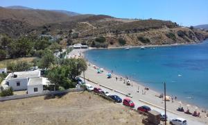 een strand met een stel auto's geparkeerd naast het water bij Pansion Katerina Skyros in Acherounes