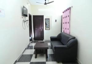 a living room with a black leather chair and a table at Oriland Cottage in Kolli Hills