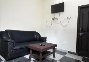 a living room with a black couch and a table at Oriland Cottage in Kolli Hills