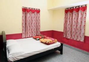 a bedroom with a bed with a red border and curtains at Oriland Cottage in Kolli Hills