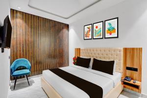 a bedroom with a bed and a blue chair at Super Townhouse OAK Chandigarh Ambala Expressway Gazipur Formerly Troy Resorts and Wellness in Zirakpur +68 photos