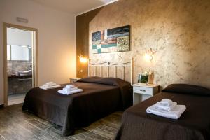 a hotel room with two beds and a bathroom at Triskell Camere & Relax in Castelluzzo