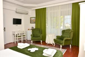 a bedroom with two green chairs and a table at MERVE BUTİK OTEL in Didim