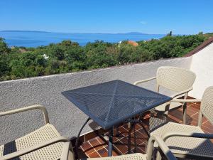 a table and chairs on a balcony with the ocean at Apartmani Belobrk Potocnica Pag in Potocnica