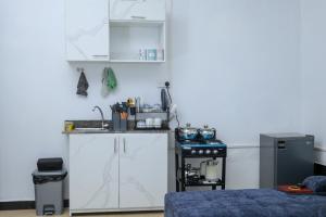 a kitchen with white cabinets and a stove at The Comfort Den in Kampala +4 photos