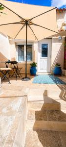 a patio with a table and an umbrella at Le secret de Santorin in Martigues