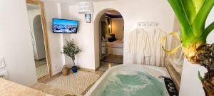 a bathroom with a tub with a tv on the wall at Le secret de Santorin in Martigues