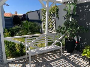 a white bench sitting under a white pergola at VILLA HELENA Crystal Apartment in Caniço