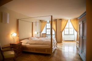 a bedroom with a canopy bed and two windows at Gästehaus im Flüsterbogen in Görlitz