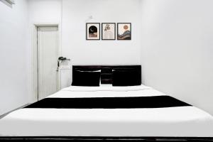 a bedroom with a large white bed with black pillows at Super Hotel O Panipat Railway Station Formerly Atithi in Pānīpat