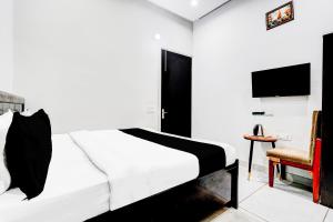 a bedroom with a white bed and a chair at Super Hotel O Panipat Railway Station Formerly Atithi in Pānīpat +28 photos