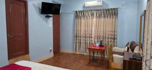 a room with a bed and a table and a television at London House Resort in Birātnagar