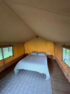 a bedroom with a bed in a tent at Camping du pont d'Oust in Peillac