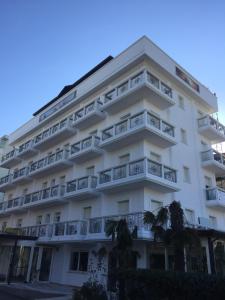 - un grand bâtiment blanc avec balcon et palmiers dans l'établissement Hotel Residence Veliero, à Riccione