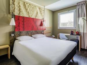 a hotel room with a large white bed and a window at Ibis Madrid Fuenlabrada in Fuenlabrada