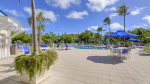a pool with chairs and tables and blue umbrellas at 4409 Ocean Pointe Suites in Tavernier