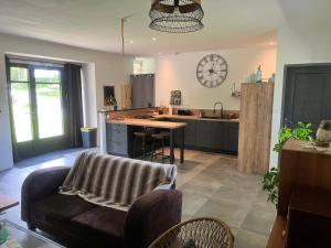 a kitchen with a couch and a clock on the wall at At Home in Cruguel