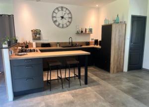 a kitchen with a counter and a large clock on the wall at At Home in Cruguel