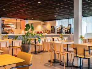 a restaurant with tables and chairs and a counter at ibis budget Amsterdam Airport in Badhoevedorp