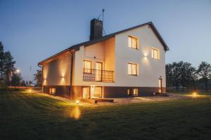 a large white house with lights on a field at MADARAS Country house in Ventava