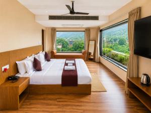 a bedroom with a large bed with a large window at Hotel The Montara Near Ganga Ghat in Rishīkesh