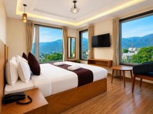 a bedroom with a large bed and large windows at Hotel The Montara Near Ganga Ghat in Rishīkesh