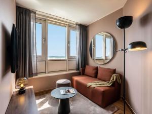 a living room with a couch and a mirror at PULLMAN Stuttgart Fontana in Stuttgart