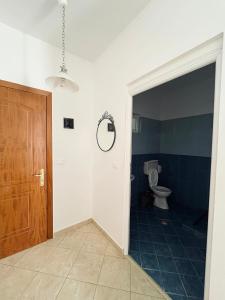 ein Badezimmer mit Toilette und Holztür in der Unterkunft Sunset Dream Guesthouse in Himarë + 40 Fotos