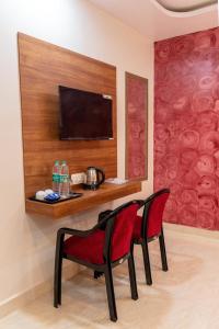 a room with two chairs and a desk with a television at Raghuvansh Hotel in Gaya +3 photos