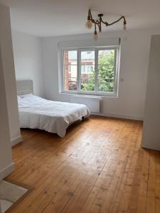 a white bedroom with a bed and a window at Gambetta in Rethel