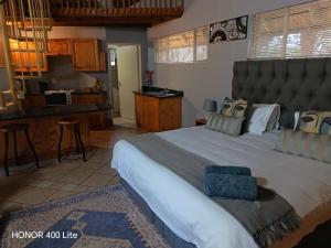 a bedroom with a large bed and a kitchen at Selati 103 Guest Cottages in Malelane